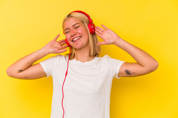 Young venezuelan woman listening music isolated on yellow background