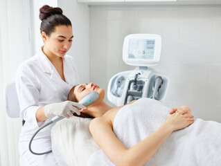 Cosmetologist using laser machine for facial treatment of client and SMAS lifting