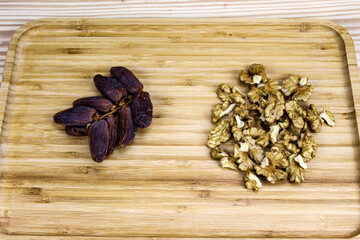 A sprig of date fruit with a walnut kernel on a wooden tray.
