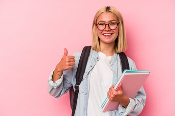 Young venezuelan student woman isolated on pink background smiling and raising thumb up