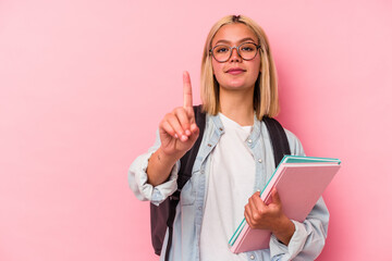 Young venezuelan student woman isolated on pink background showing number one with finger.