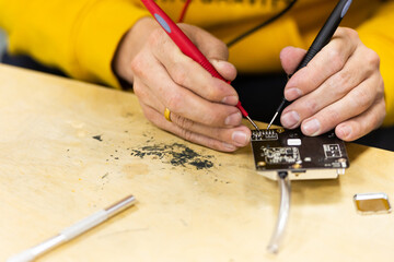 Soldering electronics on the table. Manual assembly of microelectronics. PM2.5 sensor Assembly.