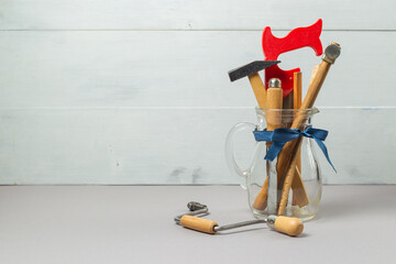 Vintage carpentry tools in a decanter with a blue gift ribbon. The concept of a professional...