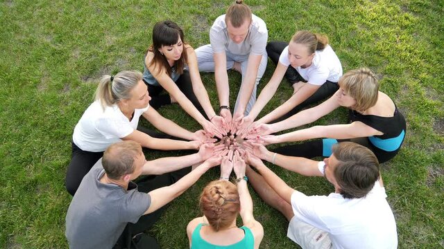 A group of young guys hold out their hands while doing yoga. A circle of human hands. A group of people putting their palms together