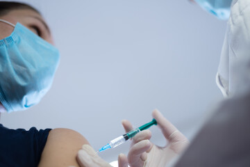 Coronavirus vaccination, doctor injecting a patient, getting first shot of covid vaccine in arm muscle. Medical doctor in protective suit and mask, process of immunization against covid-19