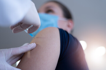 Fototapeta premium Coronavirus vaccination, doctor injecting a patient, getting first shot of covid vaccine in arm muscle. Medical doctor in protective suit and mask, process of immunization against covid-19