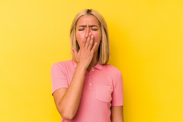 Young venezuelan woman isolated on yellow background yawning showing a tired gesture covering mouth with hand.