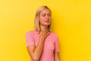 Young venezuelan woman isolated on yellow background suffers pain in throat due a virus or...