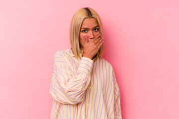 Young venezuelan woman isolated on pink background covering mouth with hands looking worried.