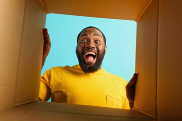 Happy man receives a package from online shop order. happy and surprised expression. cyan...