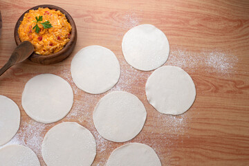 Empanadas tapas on wooden board and stuffed with vegetables and squash with bowl and flour...