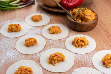 Empanadas tapas on wooden board and stuffed with vegetables and squash with bowl and flour preparation for Argentine empanadas