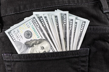 Dollars in black jeans back pocket