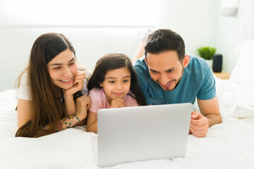 Fototapeta premium Parents and daughter laughing at online videos