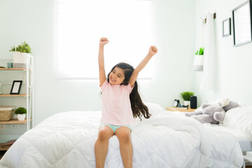 Happy kid feeling well rested in her comfy bed