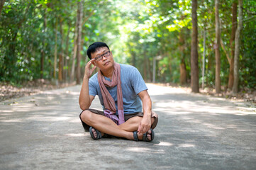 Asian man sitting lonely  in the park.Man relaxing in green natural park.Day dream working Asia people on summer vacation trip.