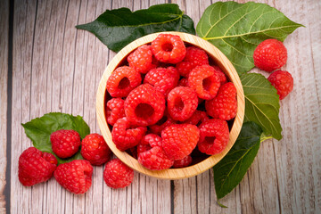 Raspberry fruit on wooden bowl in Wooden background, Raspberries with leaves on Wooden background.