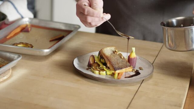 Chef drizzles sauce to finish plating a high end fish dish