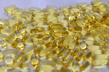 Bunch of omega 3 fish liver oil capsules in pile. Close up of big golden translucent pills texture. Healthy every day nutritional supplement. Top view