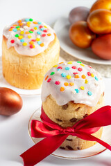 Easter cake panettone with sweet icing and golden eggs on white plate.
