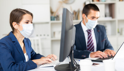 Manager in protective medical mask gives task to assistant at office