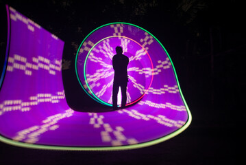Obraz na płótnie Canvas One person standing alone against a Colourful circle light painting as the backdrop 