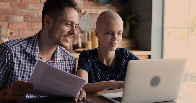 Happy Young Man Holding Medical Health History Of Cancer Patient, Helping Wife With Oncology Searching Information Of Effective Treatment, Checking Diagnosis Online. Feeling Hopeful For Full Recovery.