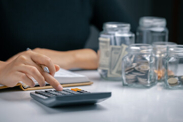 Fototapeta na wymiar Woman presses a calculator and writing make note with business stuff, Money management for the future, Personal Financial Management and Design concept.