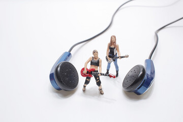 A Miniature Singer And Guitar Player Standing On A Pair Of Ear Buds