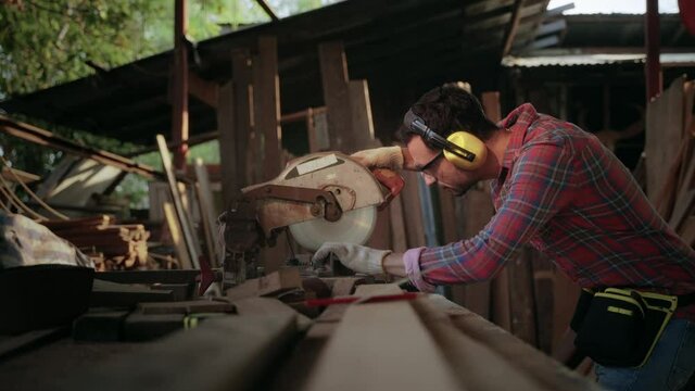 Carpenters cut work pieces with electric saws, craft furniture.
