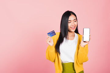 Happy Asian portrait beautiful cute young woman excited smiling hold mobile phone and plastic debit credit bank card, studio shot isolated on pink background, female using smartphone online shopping