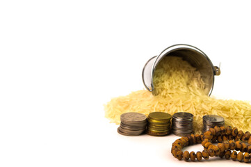Front view of prayer beads, stack of coins and rice isolated on a white background. Zakat concept.