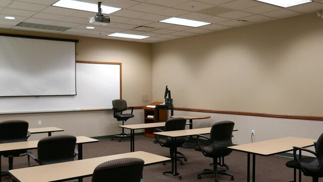 Classroom with empty chairs, computer and projection screen at front