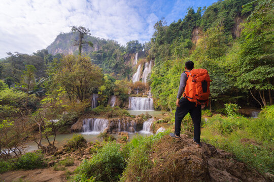 Asian man, a tourist backpacker, in Thi Lor Su Waterfall. Nature landscape of Tak in natural park in Thailand in travel trip on holiday and vacation, tourist attraction. Umphang. People lifestyle