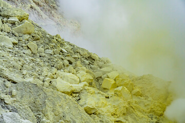 Ijen volcano crater and sulphur mining. Beautiful Landscape mountain and green lake with smoke sulfur in the morning in a Kawah Ijen volcano. Beautiful landmark from East Java, Indonesia