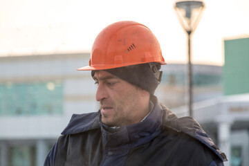 Portrait of a worker in a blue jacket with a hood at a construction site