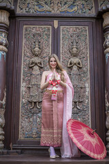 Obraz premium Beautiful girl in the Thai national bright dress with oriental makeup, travel in Thailand