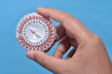Homone replacement in pill dispenser with date running in woman's hand for treate the Genitourinary syndrome of menopause