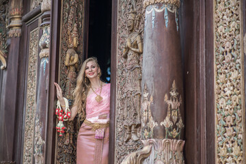 Obraz premium Beautiful girl in the Thai national bright dress with oriental makeup, travel in Thailand
