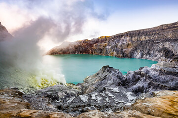Ijen volcano crater and sulphur mining. Beautiful Landscape mountain and green lake with smoke sulfur in the morning in a Kawah Ijen volcano. Beautiful landmark from East Java, Indonesia