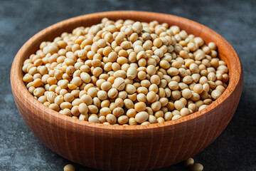 Soybeans in a wooden bowl on a gray background.