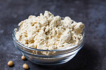 Soy protein isolate in a glass bowl on a gray background.