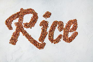 The inscription rice written in red rice on a white background. Copyspace. Topview.