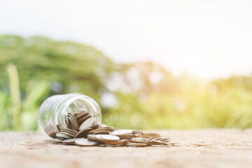 Coins spilled out of jar glass on table blur nature background, saving for future, Investment business concept.