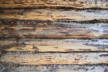 Closeup of a simple exterior wall made of horizontally stacked wooden logs, smooth, without bark...