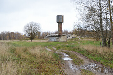 Old farm, cowshed, water tower and country road, grove, autumn, cloudy cool day