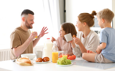 Obraz na płótnie Canvas Young happy family having healthy breakfast in morning at home
