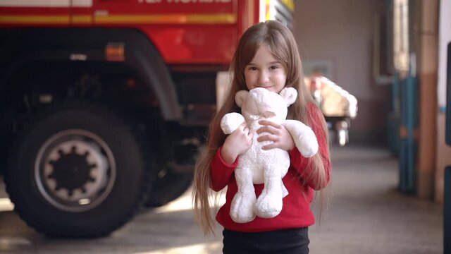 Little girl holding a toy standing in a fire guard station