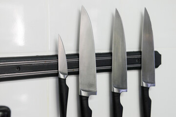 Four knives against a white wall. Kitchen equipment.