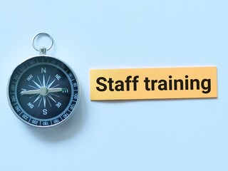 Text STAFF TRAINING written on sticky note with magnetic compass.